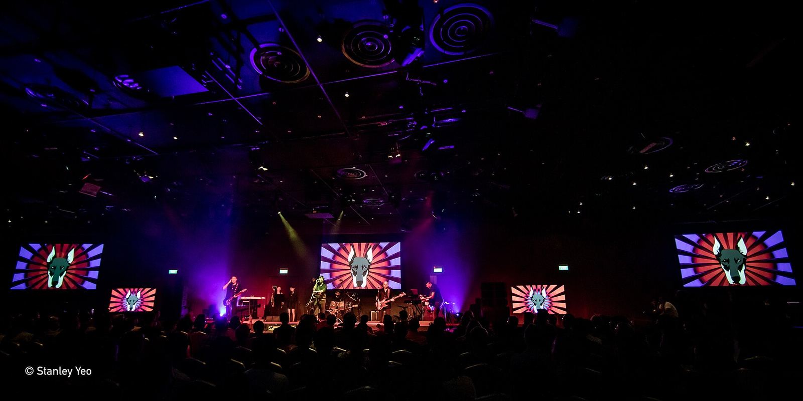 A band on a stage lit purple and red